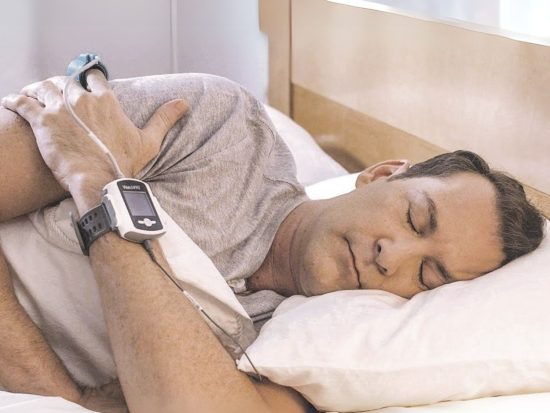 Man in bed using the WatchPat 300 home Sleep Apnoea test | SleepTest.co.uk