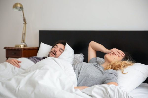 Man and woman in bed, man snoring | SleepTest.co.uk