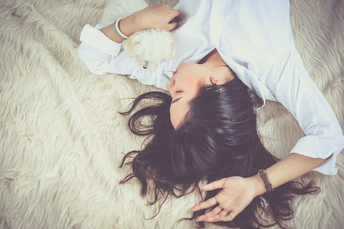 Woman laying in bed with puppy - The best sleeping position for Sleep Apnoea | SleepTest.co.uk