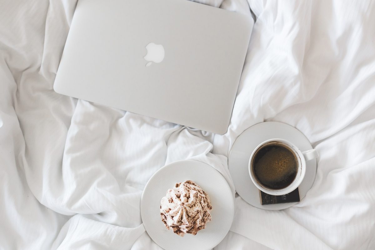 Laptop and coffee on bedsheets | SleepTest.co.uk